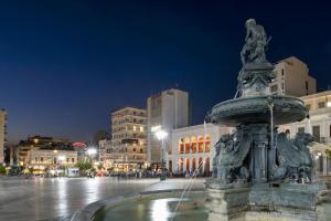 a fountain in the middle of a city at night at Roro Center Suites in Patra