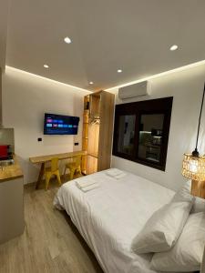 a bedroom with a bed and a desk and a television at Roro Center Suites in Patra