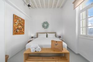 ein weißes Schlafzimmer mit einem Bett und einem Fenster in der Unterkunft Rabagas Suites - In The Heart of Sifnos in Apollonia