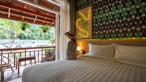 a woman wearing a hat standing next to a bed at Senglao Boutique Hotel Luang Prabang in Luang Prabang