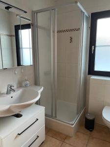 a white bathroom with a shower and a sink at Panoramablick in Lechbruck
