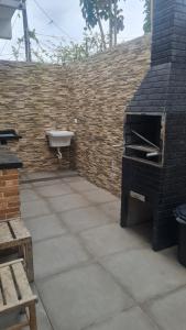 ペルイベにあるKitnets Peruíbe casa 02のレンガの壁のパティオ(屋外オーブン付)