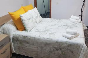 a bedroom with a bed with white sheets and yellow pillows at Vacacional Tegueste 2ºD in Vecindario +3 photos
