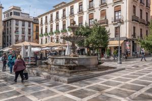 グラナダにあるAlhambra Centro Apartamentoの市の通りの噴水を通り抜ける女