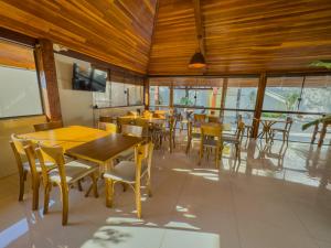 a restaurant with wooden ceilings and tables and chairs at Pousada Recanto Dourado in Bonito