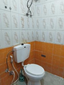 y baño con aseo blanco y azulejos de color naranja. en Grand Square Hostel Luxor, en Luxor