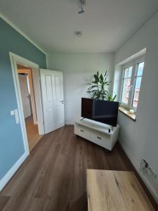 a living room with a flat screen tv on a cabinet at Gemütliche Einliegerwohnung in Drantum
