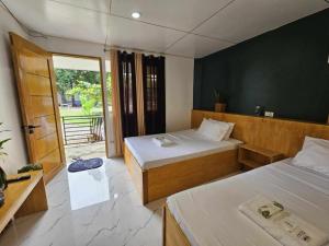 a bedroom with two beds and a door to a balcony at Vhora Inn Sibuyan in Magdiwang +34 photos