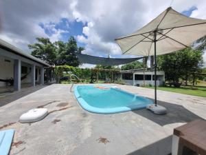 a swimming pool with an umbrella next to a house at Chácara Cantinho dos Sonhos in Chapada dos Guimarães