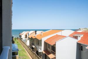 eine Reihe von Häusern mit dem Ozean im Hintergrund in der Unterkunft Aptos completo com vista mar pé na areia em Barra Velha em condomínio Resort com Spa, Piscina, quadra de futebol, Sala de jogos, brinquedoteca, Complexo com diversos comércios in Barra Velha
