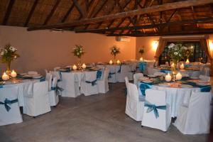 a room with white tables and chairs with blue bows at Castello Guesthouse Vryburg in Vryburg