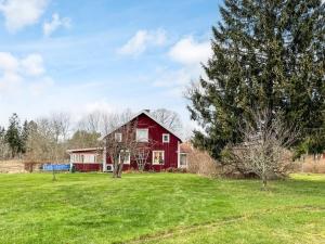 a red barn in the middle of a field at 4 person holiday home in HALLSTAVIK in Herräng