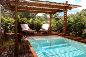 a swimming pool with a wooden pergola and a swimming poolvisor at Aura Anse Marcel in Anse Marcel 