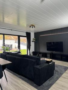 a living room with black furniture and a flat screen tv at Jacks Ferienhaus Braunlage nähe der Seilbahn in Braunlage