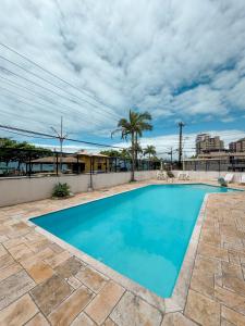 una piscina con agua azul y palmeras en Apt Pé na Areia - Praia Martim de Sá - Espaço Gourmet na Varanda e Piscina, en Caraguatatuba