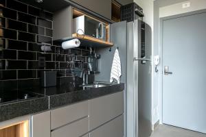 a kitchen with a sink and a refrigerator at Studio Style - Vila Olímpia in Sao Paulo