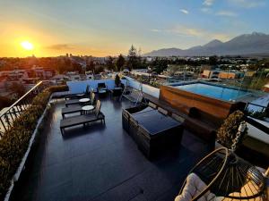 una terraza en la azotea con piscina, sillas y puesta de sol en Vita Hoteles Arequipa, en Arequipa