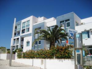 een wit gebouw met een palmboom ervoor bij Bay View Apartments in Albufeira