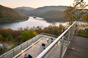 a deck with two chairs and a view of a river at Umbrella Resort & Villas in Prishtinë
