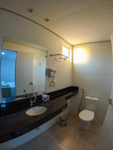 a bathroom with a sink and a toilet and a mirror at Pousada Recanto Dourado in Bonito
