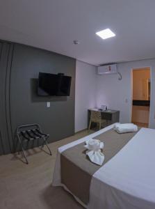 a hotel room with a bed and a flat screen tv at Pousada Recanto Dourado in Bonito