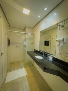 a bathroom with a sink and a shower and a mirror at Pousada Recanto Dourado in Bonito