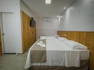 a bedroom with a large white bed with white pillows at Pousada Recanto Dourado in Bonito