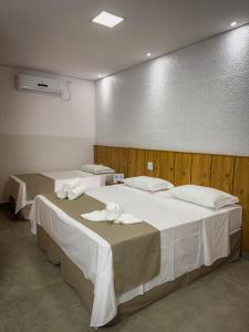 a room with two beds with white sheets and towels at Pousada Recanto Dourado in Bonito