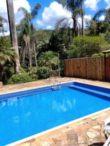a swimming pool in a yard with palm trees at Villa Bottaro - chalé amarelo in Nova Lima