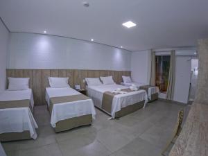 a hotel room with three beds and tables at Pousada Recanto Dourado in Bonito