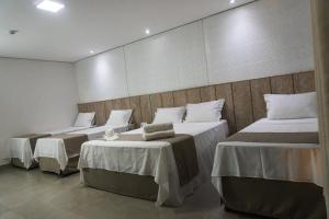 a room with three beds with tables in it at Pousada Recanto Dourado in Bonito