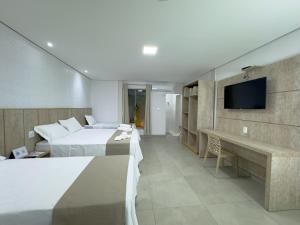 a hotel room with two beds and a flat screen tv at Pousada Recanto Dourado in Bonito
