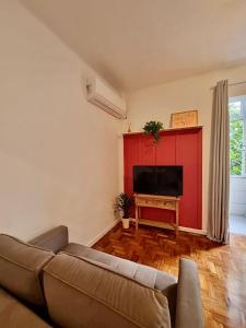 a living room with a couch and a flat screen tv at Loft espaçoso a 300m da praia in Rio de Janeiro