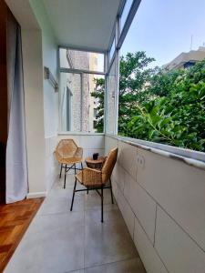 a balcony with two chairs and a large window at Loft espaçoso a 300m da praia in Rio de Janeiro