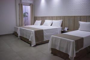 a hotel room with two beds with white sheets at Pousada Recanto Dourado in Bonito