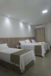 a room with two beds and two tables in it at Pousada Recanto Dourado in Bonito