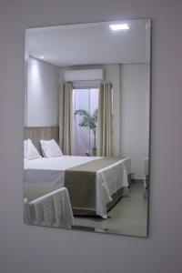 a mirror reflecting a bedroom with a bed and a window at Pousada Recanto Dourado in Bonito