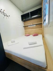 Cette petite chambre comprend un lit avec des draps blancs. dans l'établissement Žaba-Kamp Dalmacija, à Privlaka