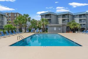 a swimming pool with chairs in front of a building at Sea Cabin 147 - 2nd Row - Cherry Grove Section in Myrtle Beach