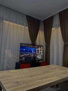 a living room with a table and a television at Umbrella Resort & Villas in Prishtinë