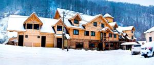 a large wooden house with snow on the roof at Šum Apartmani - Stara planina in Crni Vrh