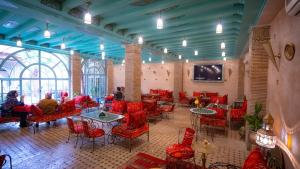 a room with red chairs and tables and a tv at Riad Golden Mansour in Meknès