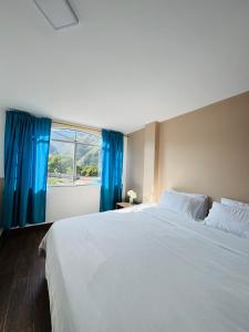 a bedroom with a large white bed with blue curtains at Luxury Penthouse with Jacuzzy 6 bedroom in Baños