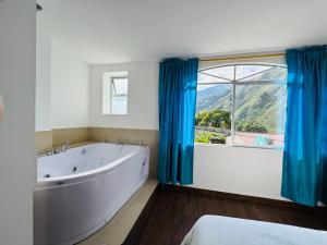 a bathroom with a tub and a large window at Luxury Penthouse with Jacuzzy 6 bedroom in Baños