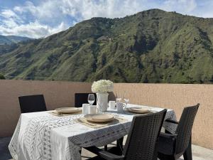 a table with a white tablecloth and chairs with a mountain at Luxury Penthouse with Jacuzzy 6 bedroom in Baños