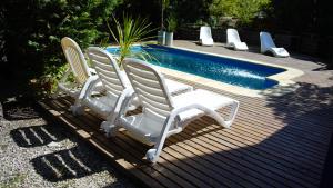 two white chairs sitting next to a swimming pool at Apart Finiterra in Mar de las Pampas
