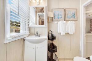 a white bathroom with a sink and a window at Suncatcher Cottage 1508-2nd Avenue A in Tybee Island +31 photos