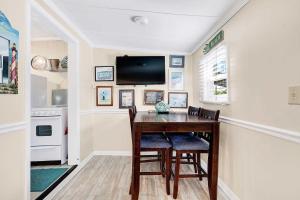 a dining room table with chairs and a television on a wall at Suncatcher Cottage 1508-2nd Avenue A in Tybee Island