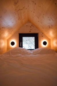 a room with a window and a bed with white sheets at Căsuța din livadă in Măneciu