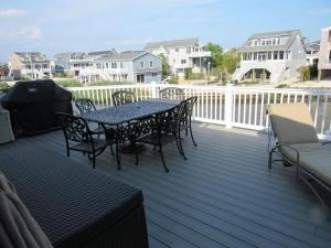a patio with a table and chairs on a deck at Lagoon Front Home In Harvey Cedars in Harvey Cedars